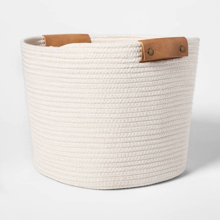 A white woven basket with leather handles