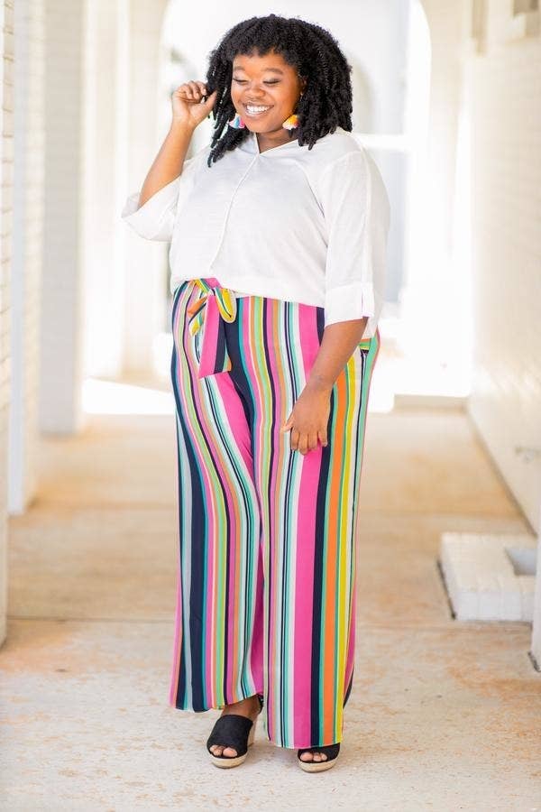model in wide-leg pants with bright multi-colored vertical stripes and a tie waist