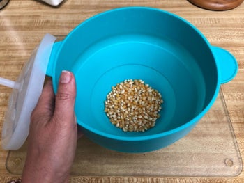 A reviewer holding the popper with unpopped kernels