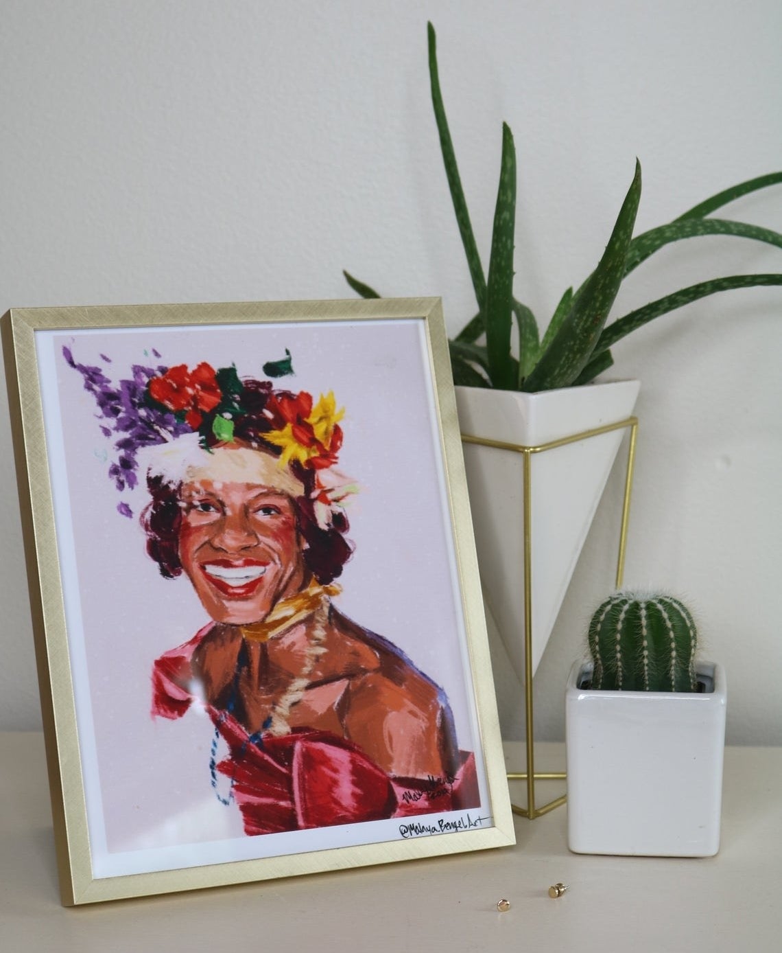 A colorful painted print of Marsha P. Johnson wearing an evening gown, flower crown, and showing off her dazzling smile 