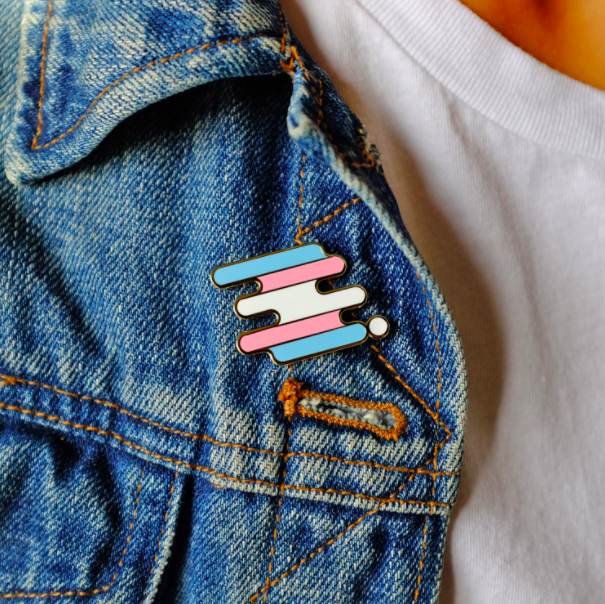 The Trans flag colors on a pin on a jean jacket