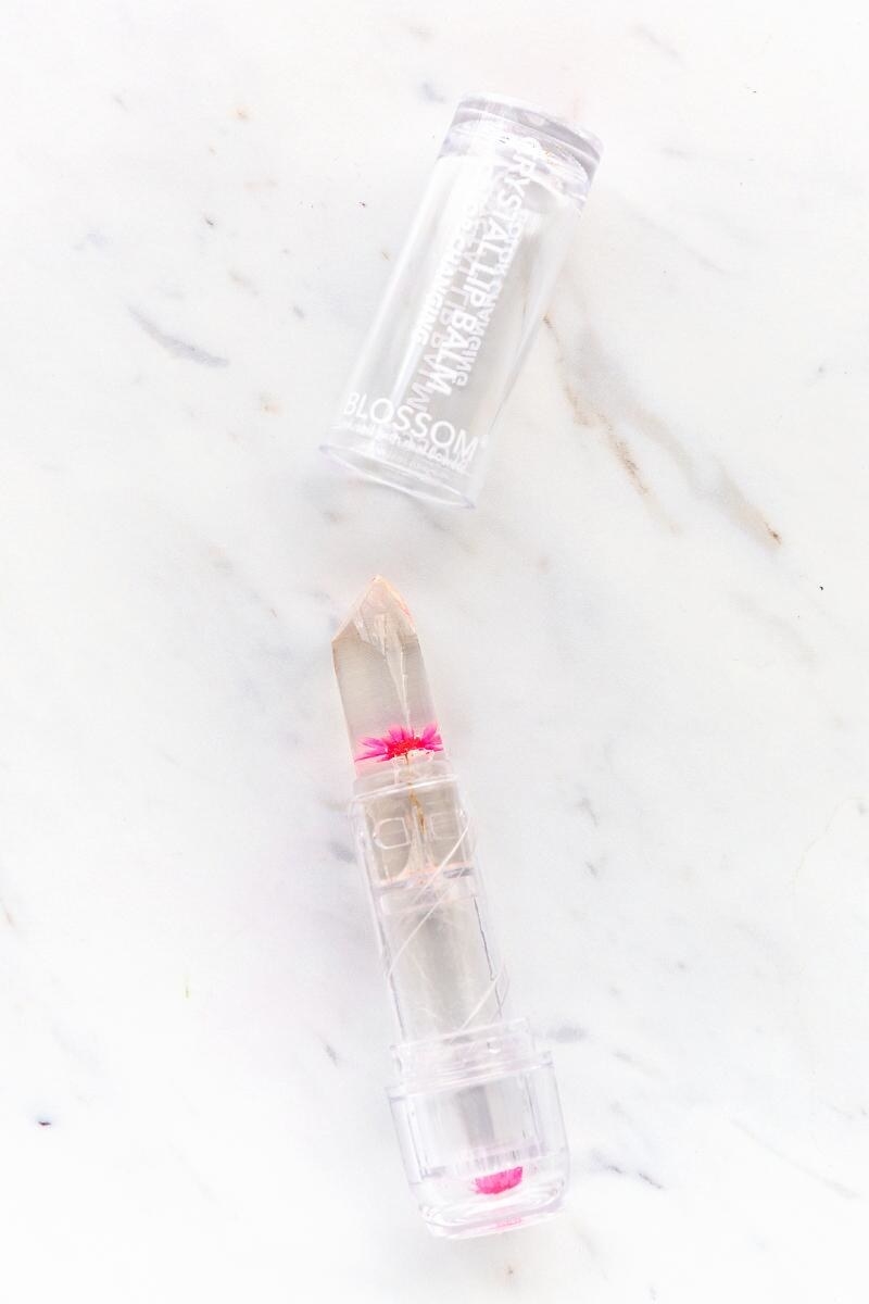 clear lip balm in lipstick shape with a pink flower inside