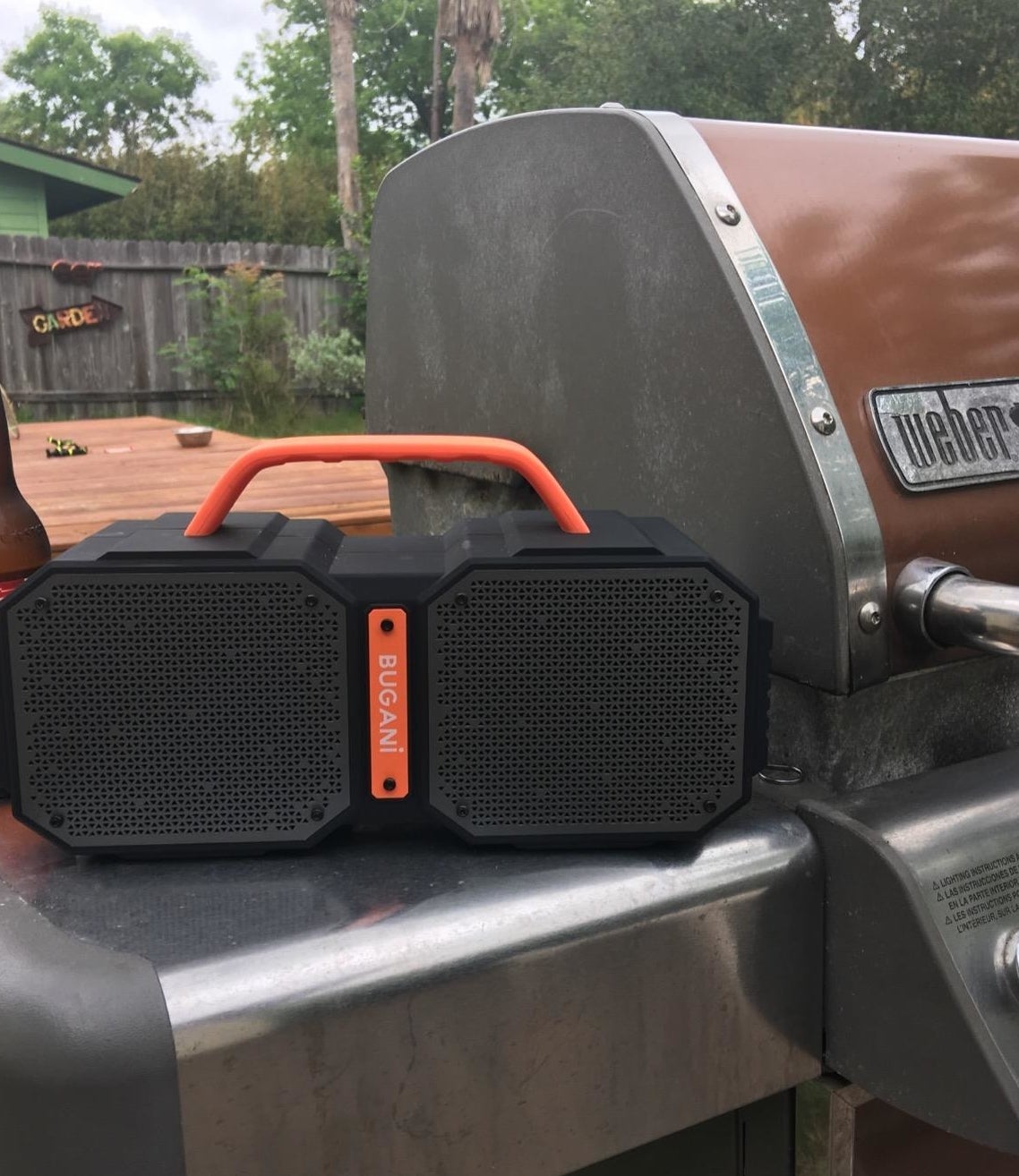 black and orange boombox-shaped speaker sitting on grill side table