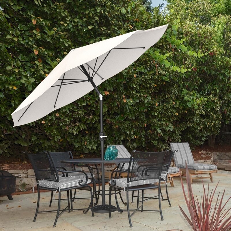 An opened white umbrella with a black pole and base and a metallic crank handle 