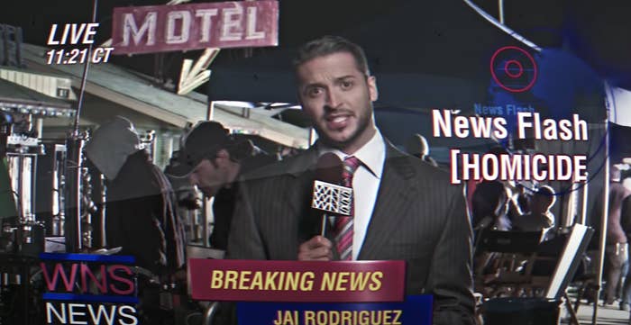 Jai Rodriguez standing in front of a motel and giving a news broadcast