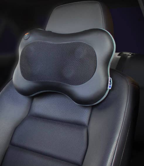 The massager attached just below the headrest of the driver&#x27;s side car seat. It has four protruding massagers and heat-proof fabric in the center.