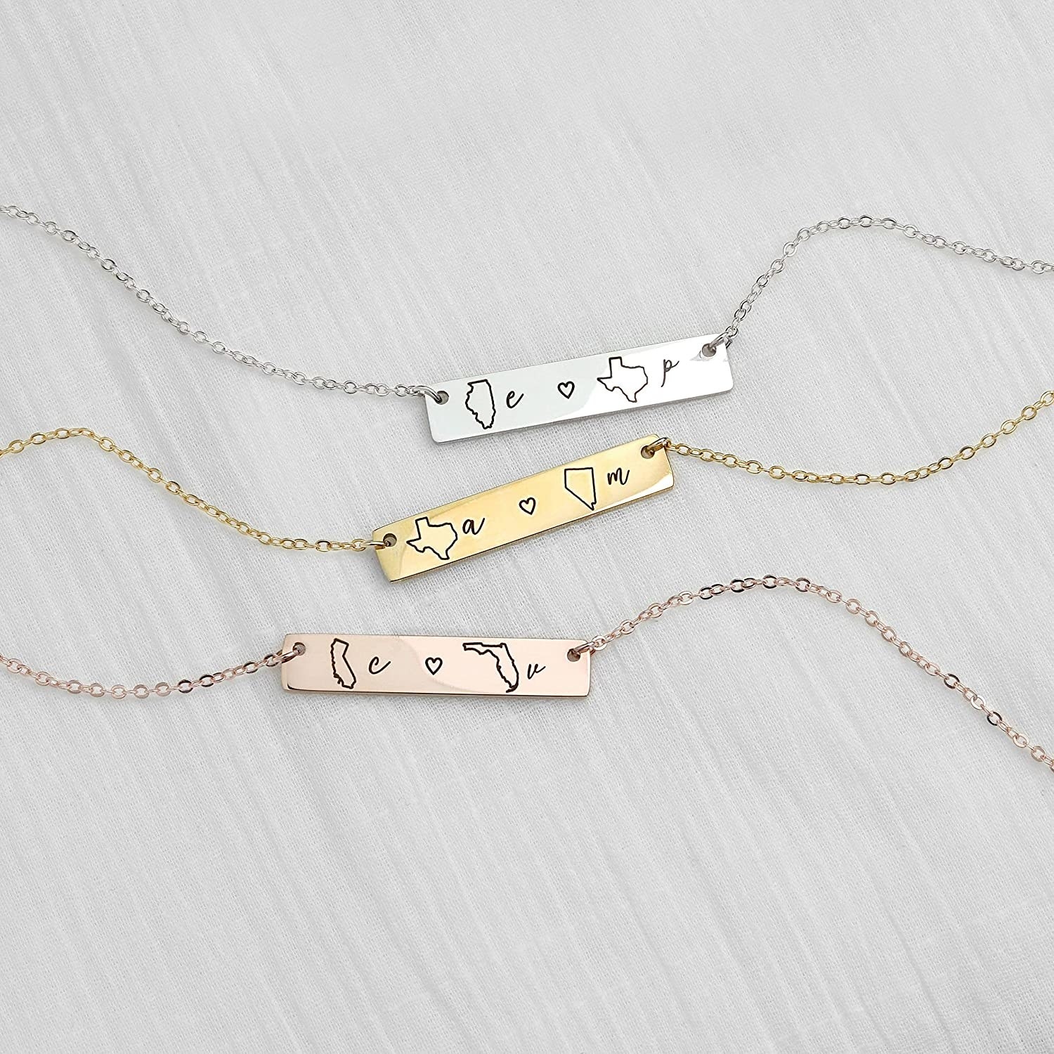 Necklaces in silver, gold, and rose gold with a bar that has different letters and state outlines on them 