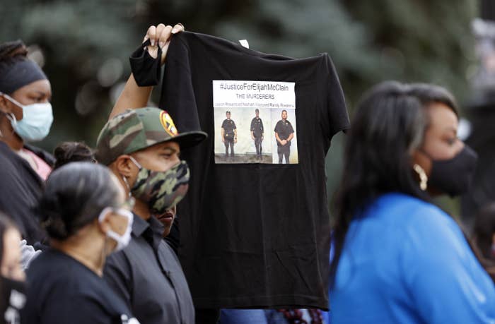 Someone holds up a T-shirt that says "#JusticeForElijahMcClain" in Denver, June 19.