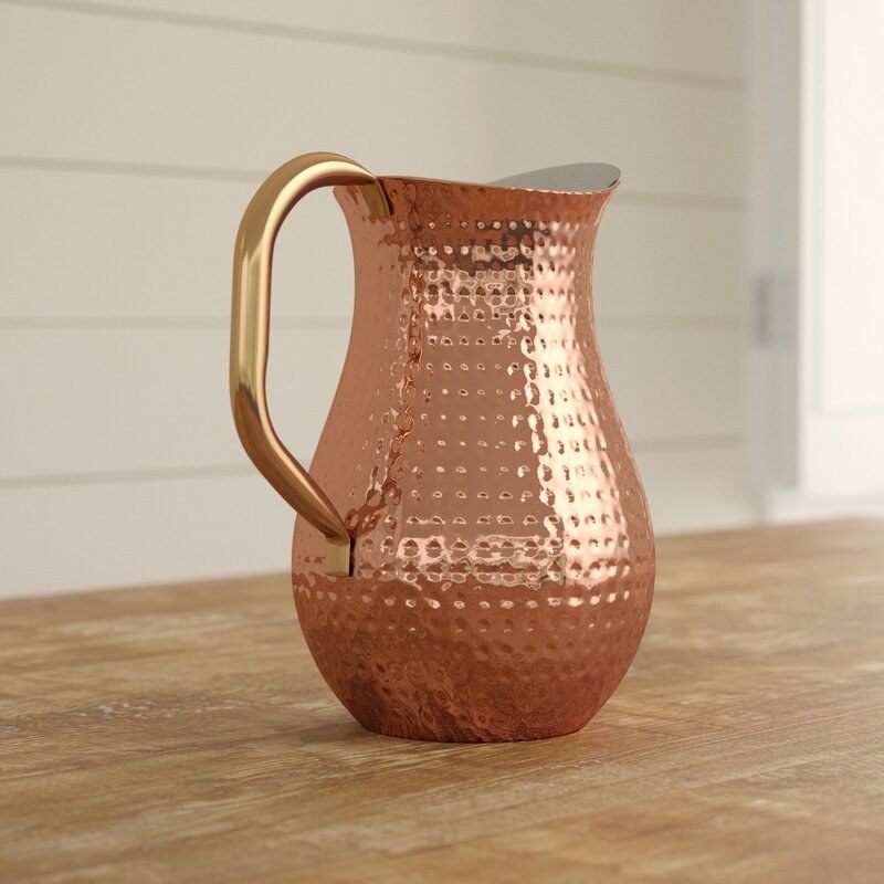 A shiny copper pitcher with a smooth handle 