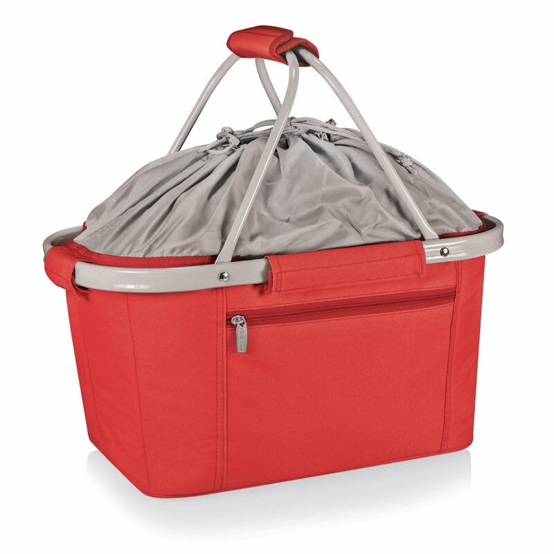 A red picnic basket with a side pocket, gray metal handles, and soft cloth tie top