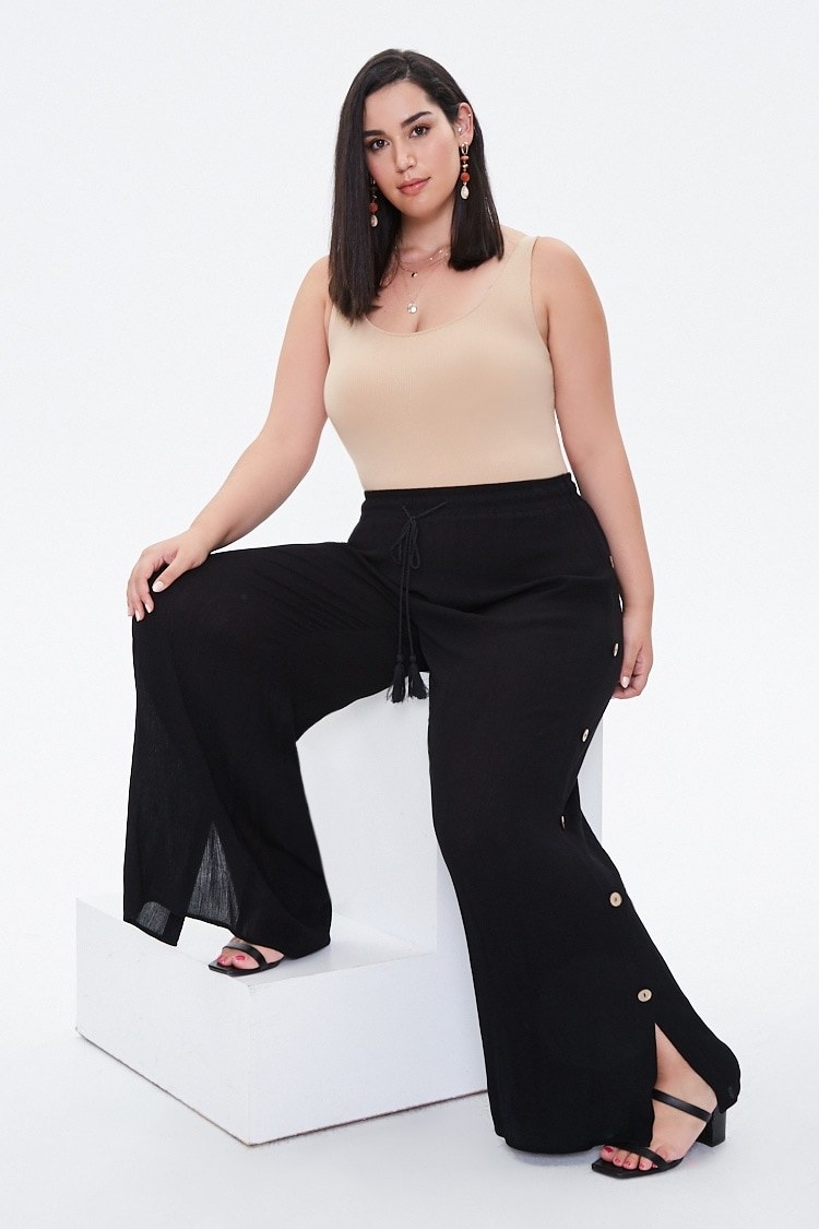 Model wearing semi-sheer woven pants with a mock tearaway design with silver button accents and a drawstring waist