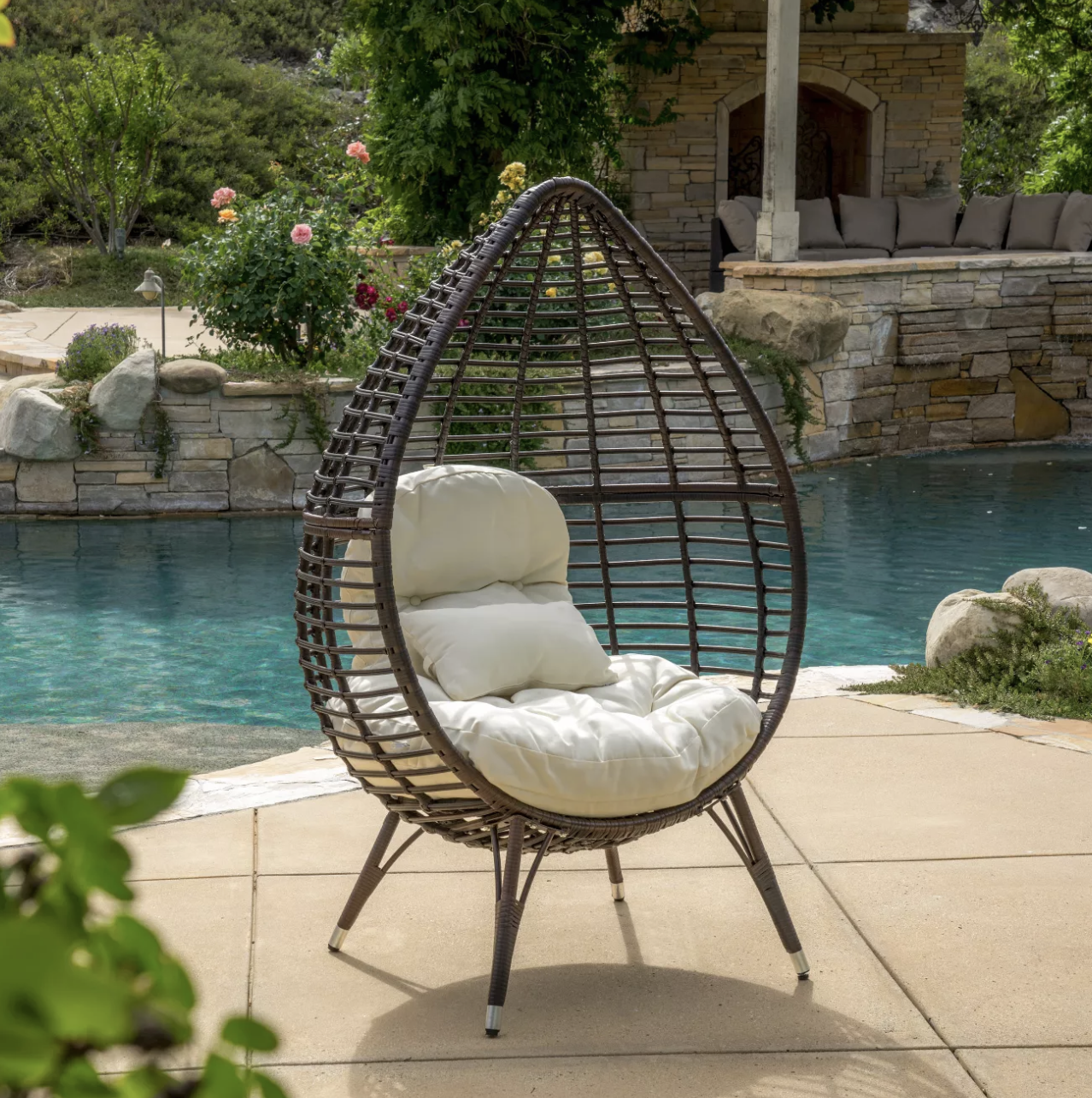 teardrop wicker chair with two tan fluffy pillows
