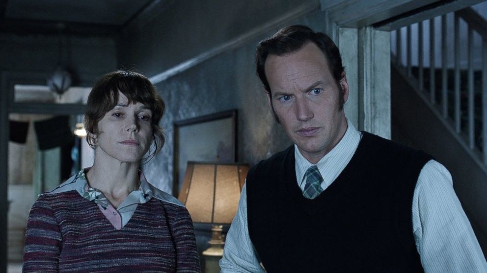 Actor Patrick Wilson looking concerned as he looks on at a haunted house.