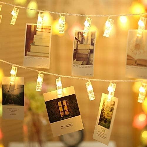 A string of clip on fairy lights with photos attached to them 