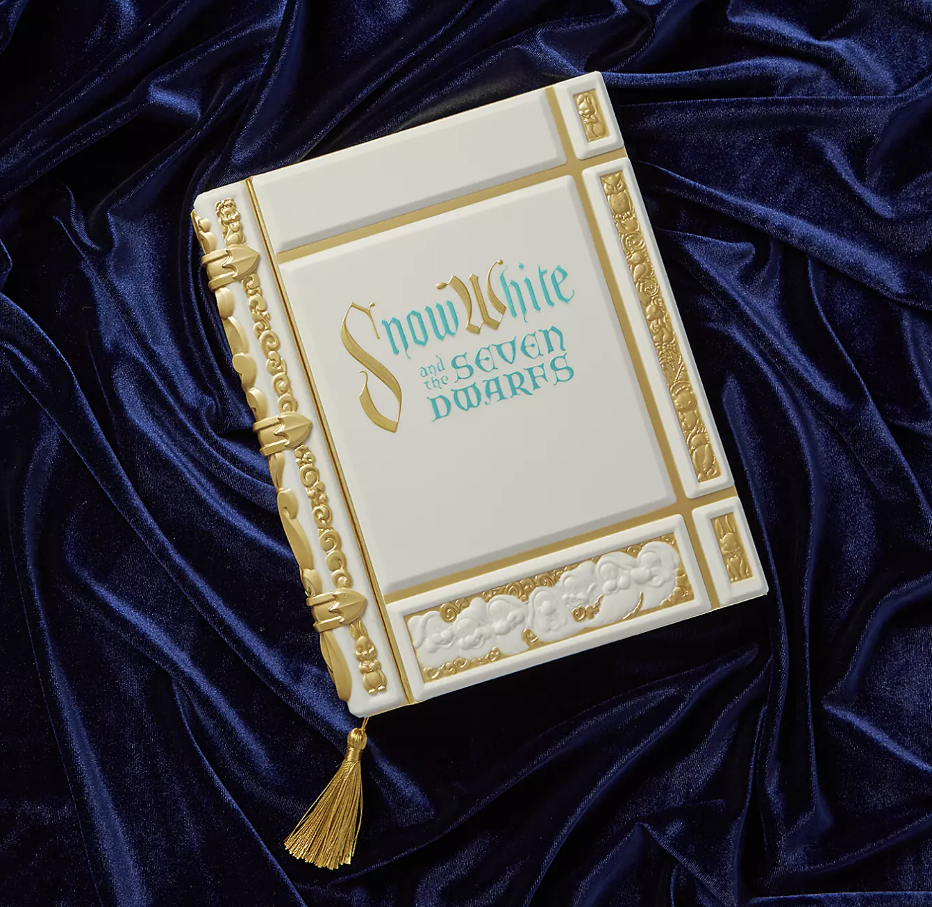 the journal, which has golden filigree and accents, gilded edges, and a golden tassel bookmark
