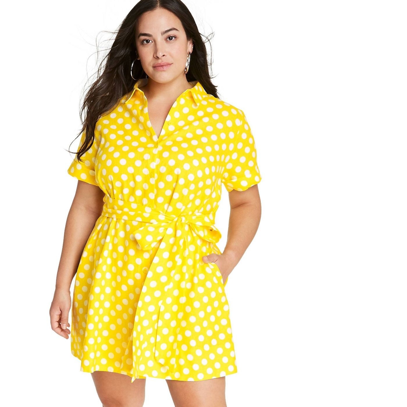 A model in a yellow dress with white polka dots and a tie string waist 