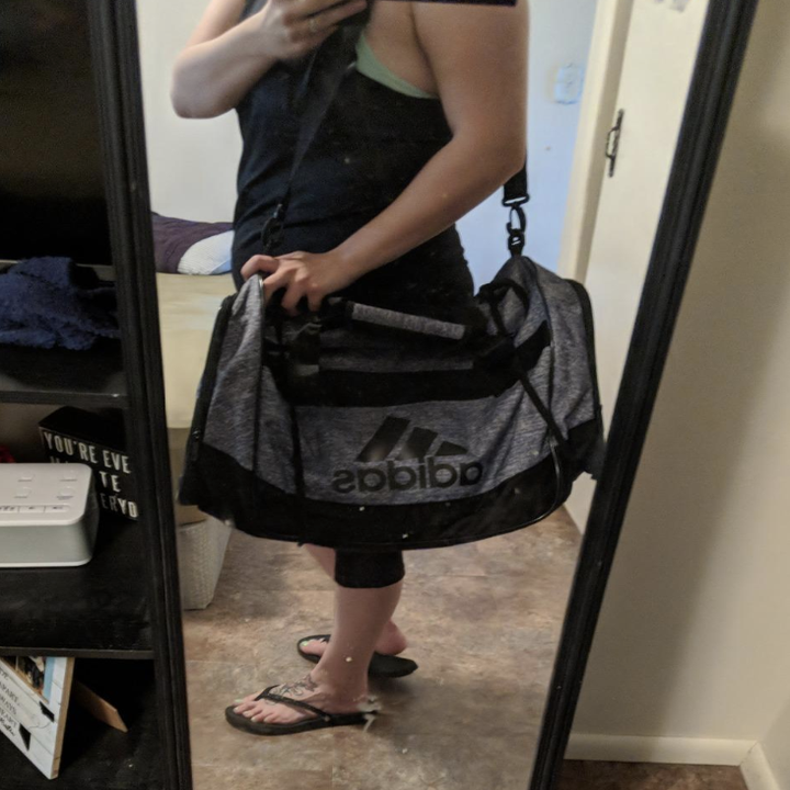 A reviewer with the strap of the gray duffel on her shoulder 