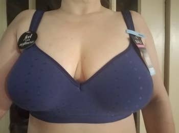 A plus-size reviewer with larger boobs wearing a navy blue version of the bra