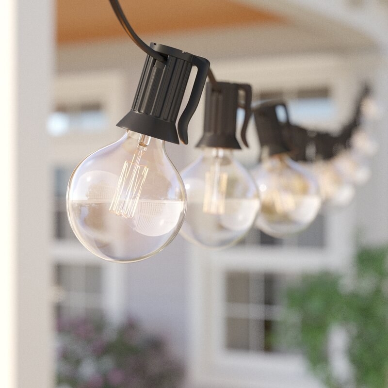 Round light bulbs that are not illuminated hanging from a black string