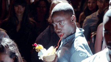 Winston drinking a fruity tropical drink in New Girl while making a funny face