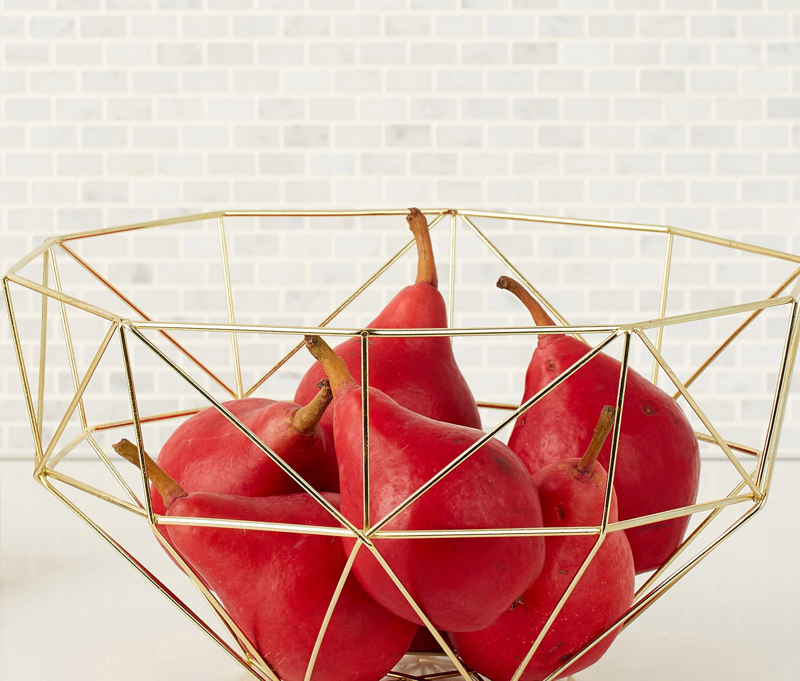 A metal bowl with pears inside it