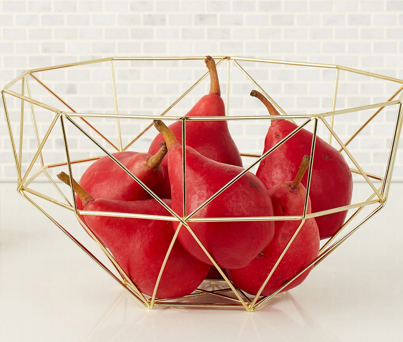A metal bowl with pears inside it