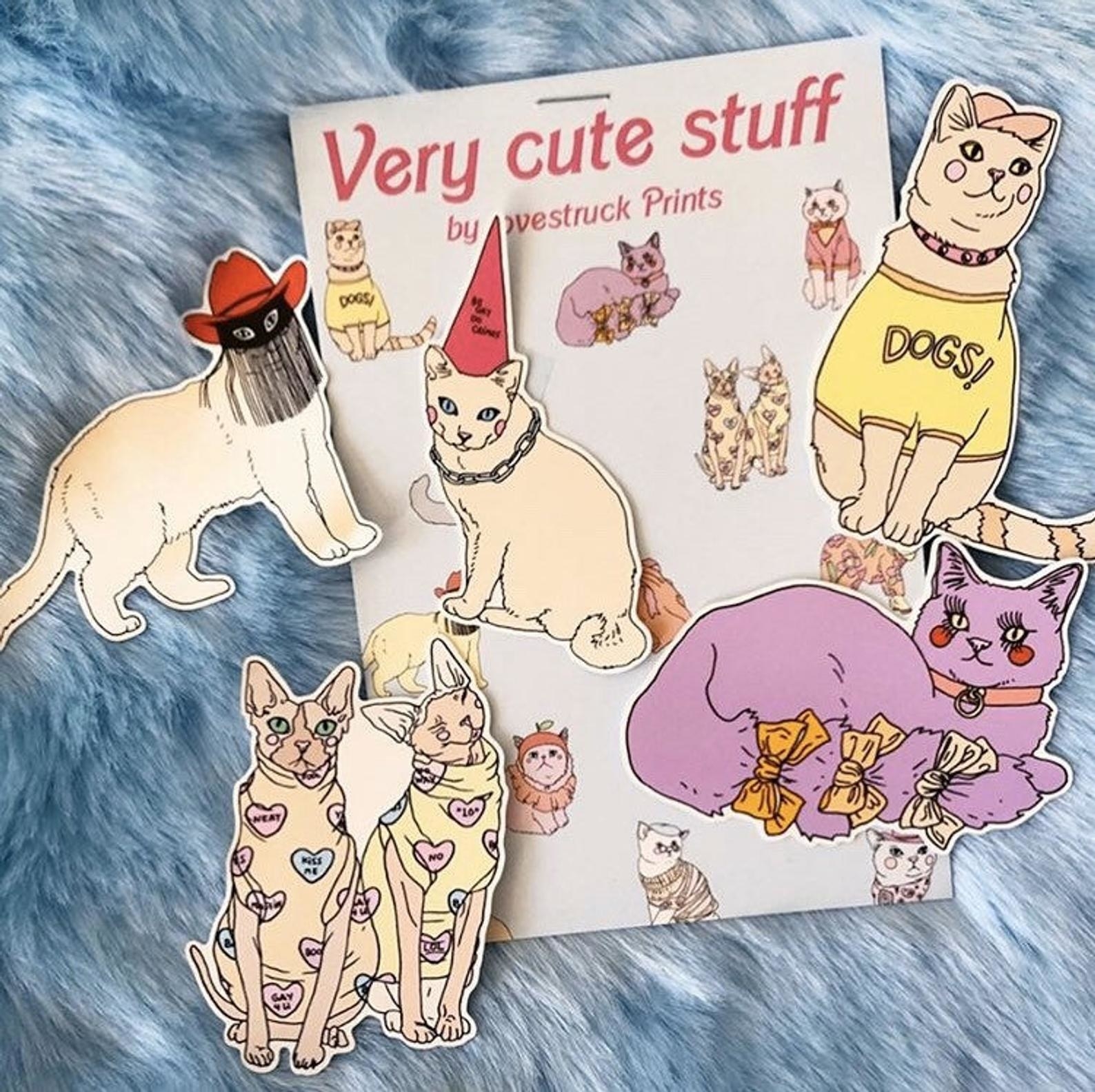 Five stickers of illustrations of different kinds of cats wearing hats, bows, and other clothes
