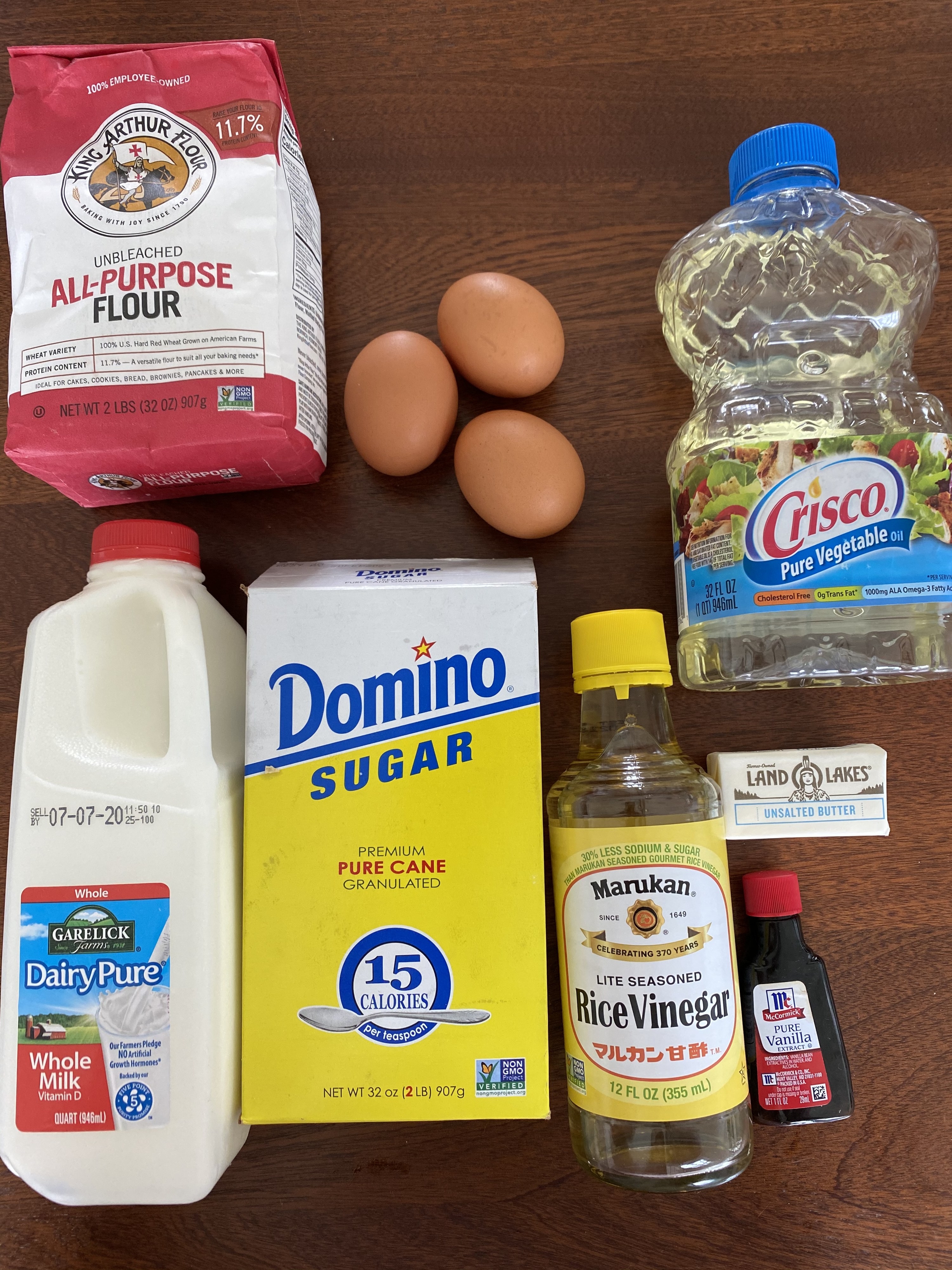 Ingredients for Japanese fluffy pancakes on a countertop including milk, sugar, eggs, flour, vanilla, butter, vegetable oil.