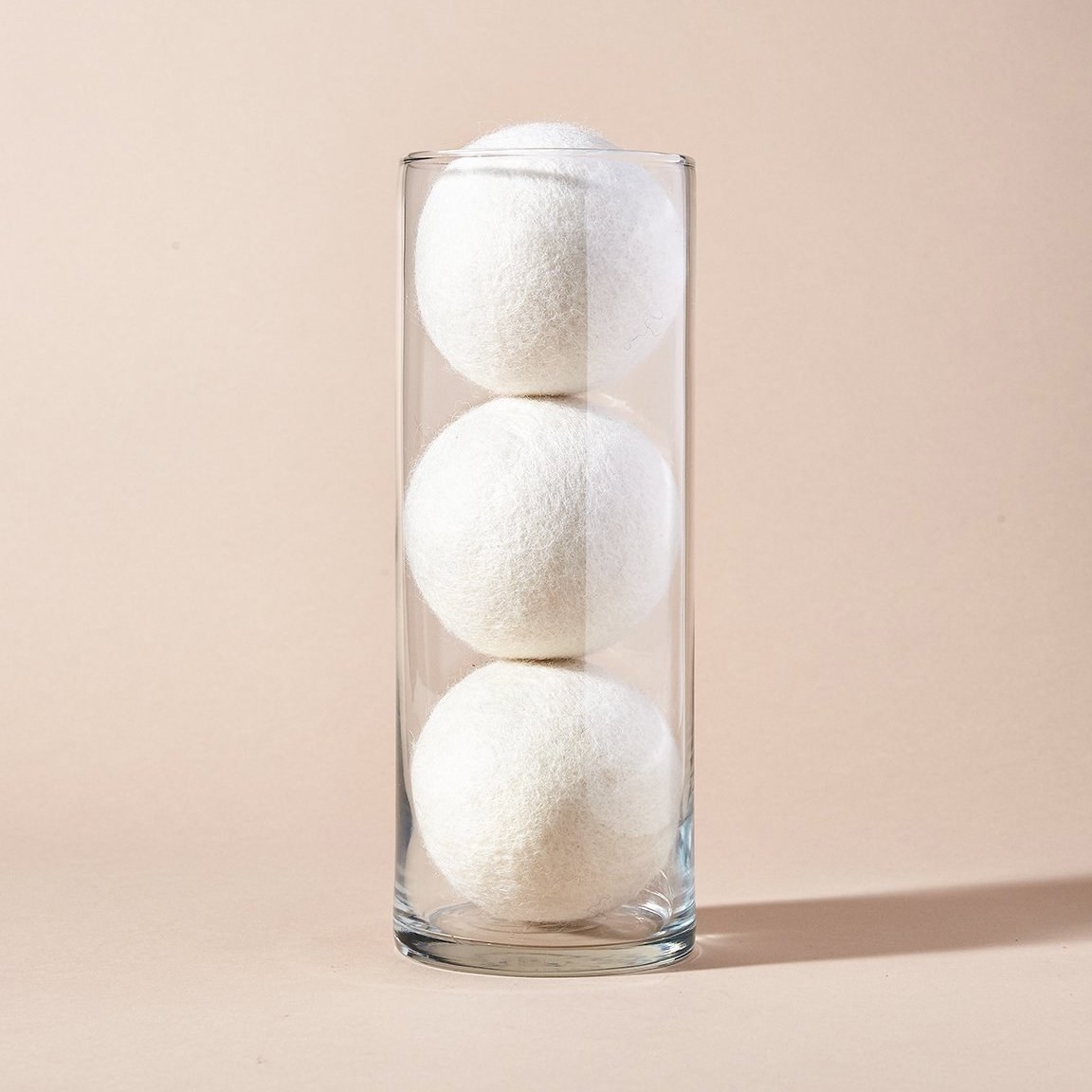 A glass vase with the three large white wool balls