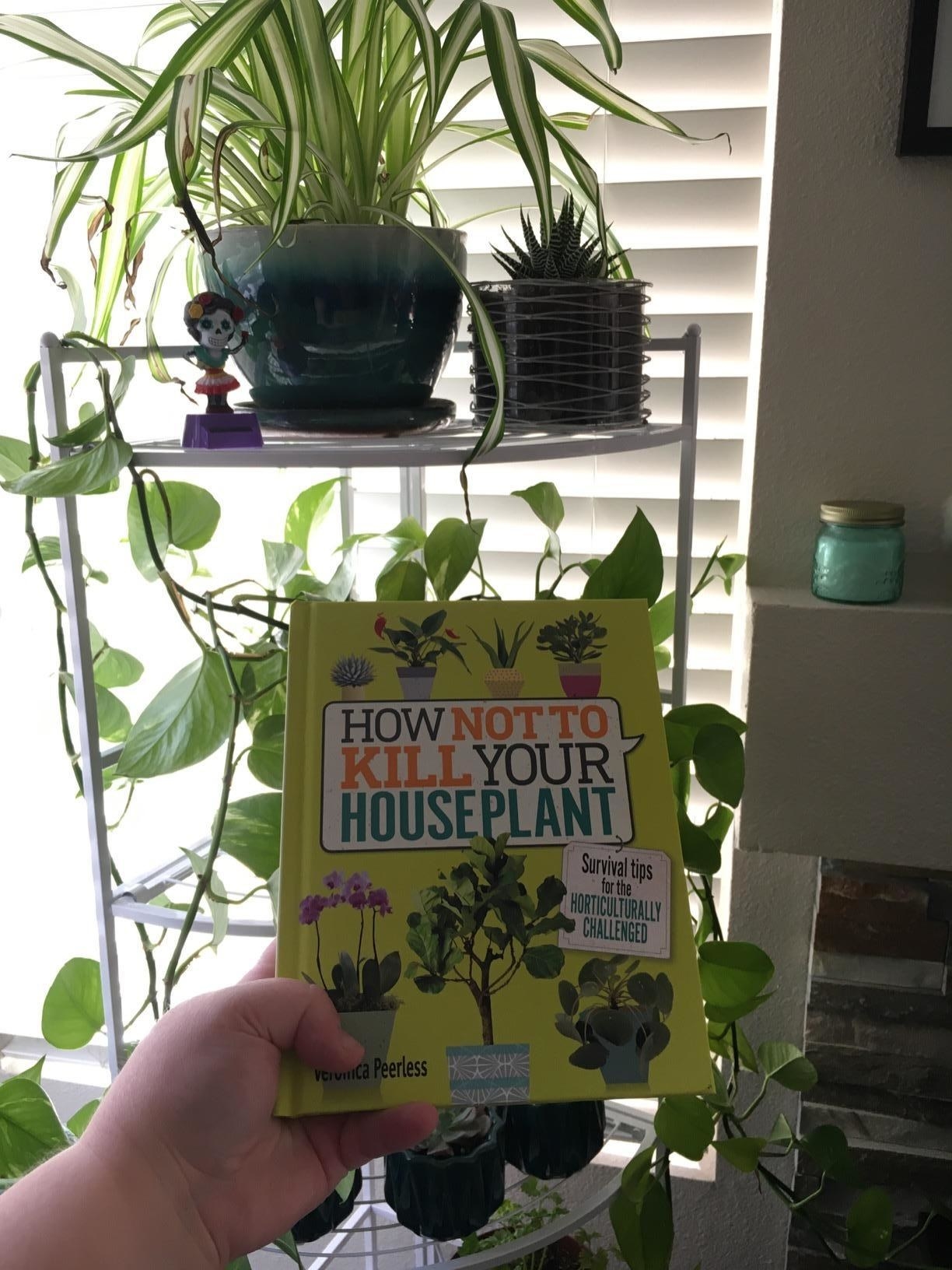 Reviewer holding the book in front of several healthy-looking plants