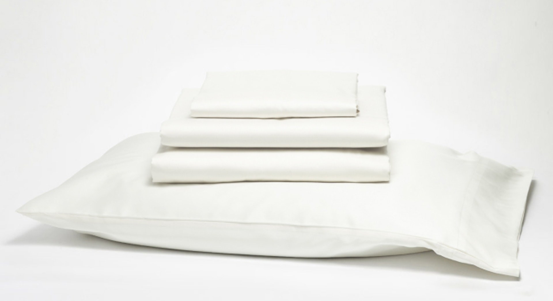 Pillow with white sheets stacked on top 