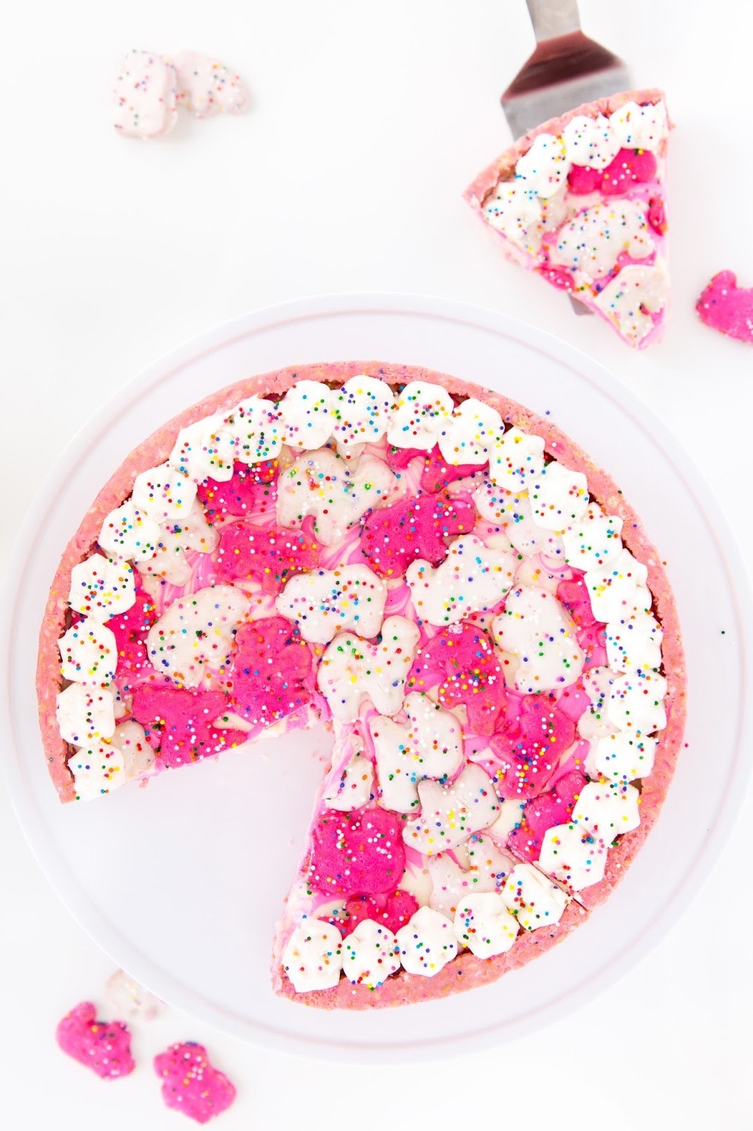A pink and white cheesecake topped with frosted circus animal crackers