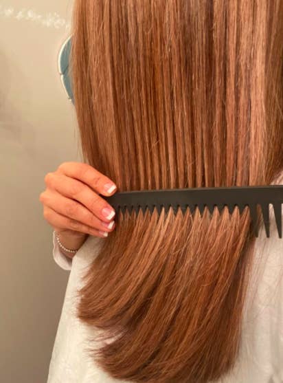 Reviewer uses detangling comb to work out knots in their reddish brown hair