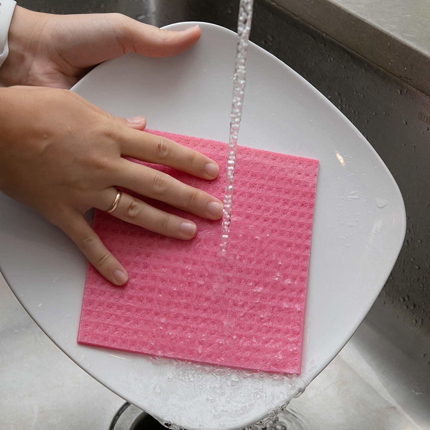 A dish being washed using a pink sponge cloth