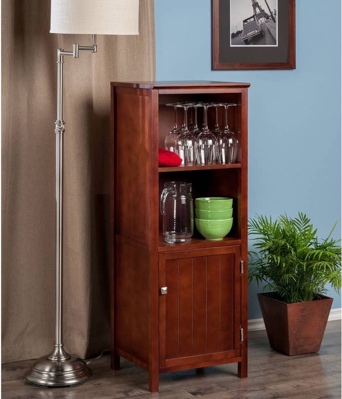 a tall brown wooden cabinet with two shelves and a closed cabinet closes to the base