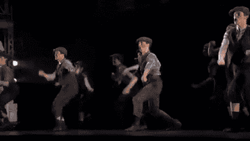a group of teens dancing dressed as news paper delivery boys