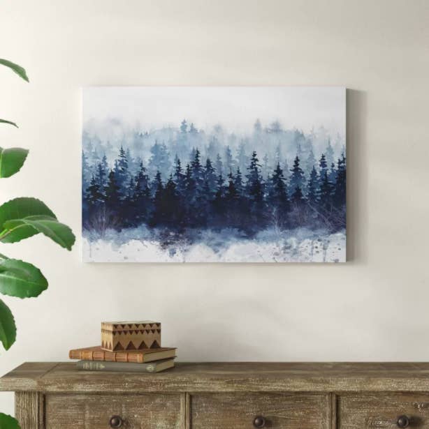An &quot;Indigo Forest&quot; art print with blue trees and fog hanging above a wooden dresser