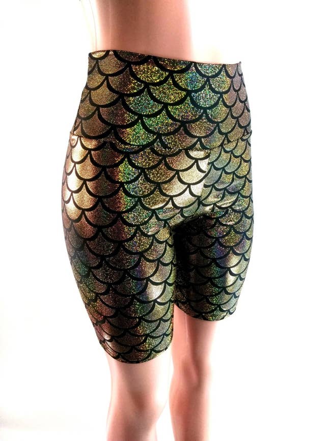 A mannequin in a pair of glittery gold mermaid scale printed bike shorts that fall above the knee 