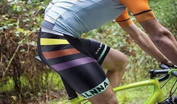 A biker waiting black bike shorts with yellow, orange, and purple stripes that falls above the knee 