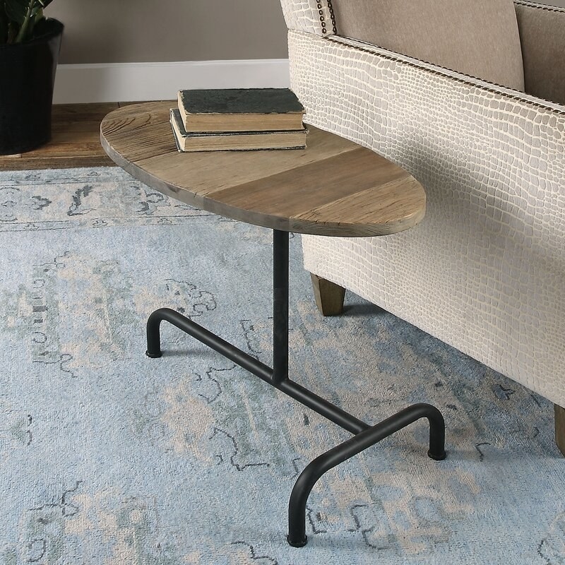 The table featuring an oval, elm-finish top and matte black metal legs