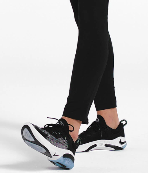 Model wears a pair of black and blue Nike Joyride Run Flyknit sneakers