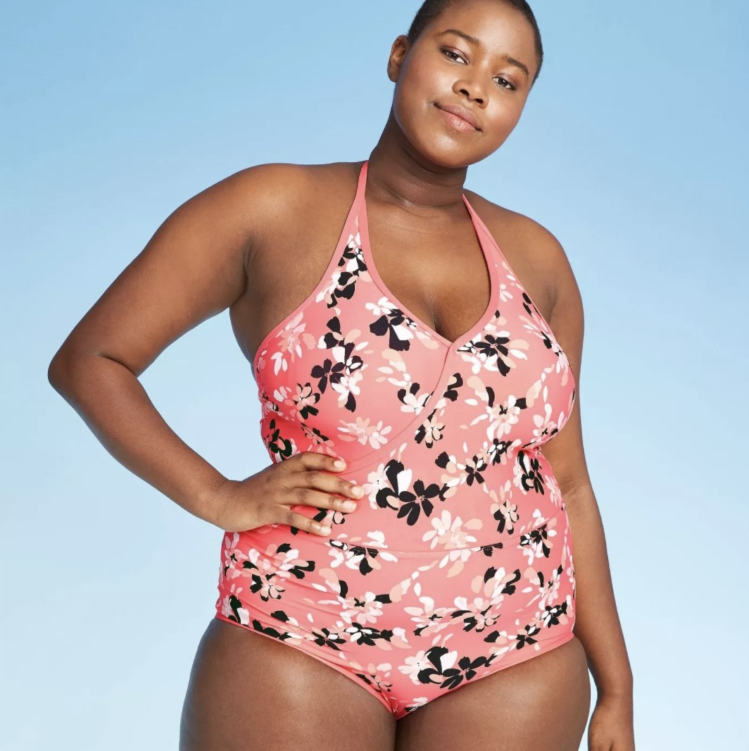 A model in a halter one piece with floral designs on it 