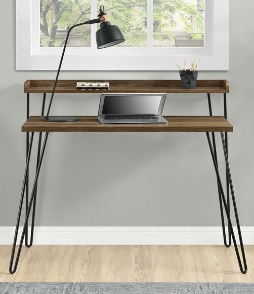 A wooden desk with black metal legs and a single shelf