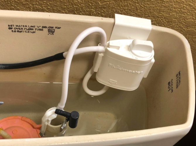 A reviewer photo of the installed system, which clips on to the tank and attaches to two of the toilet's internal tubes