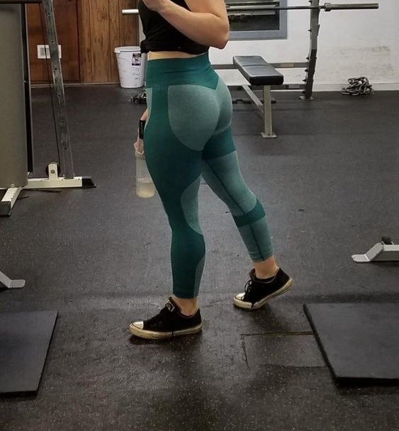 Reviewer wearing the two-toned light and dark green leggings, and showing their back full coverage 