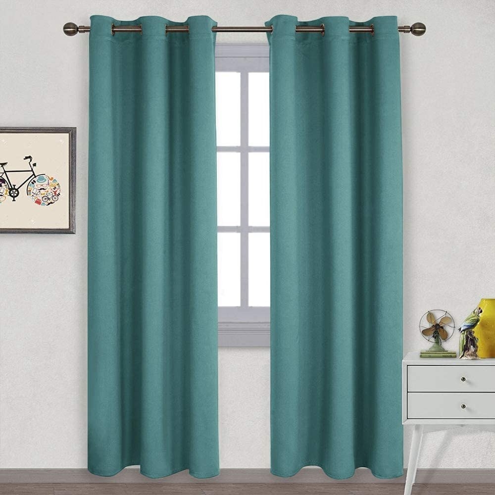 A set of teal blackout curtains hung up on a window 