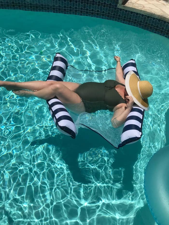 A reviewer floating on the inflatable hammock in a pool