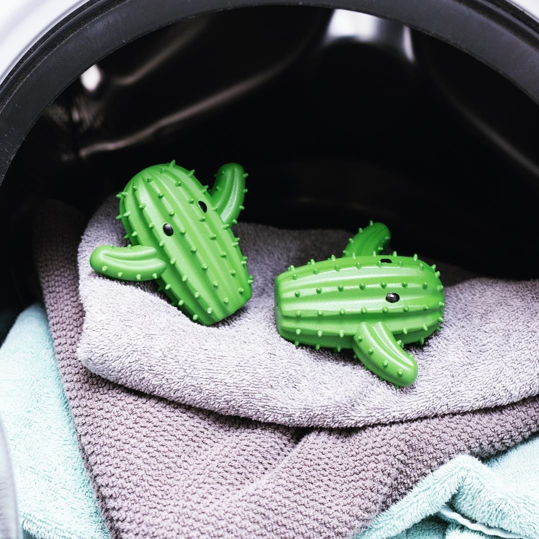 A pair of cute cactus-shaped dryer balls on a pile of towels