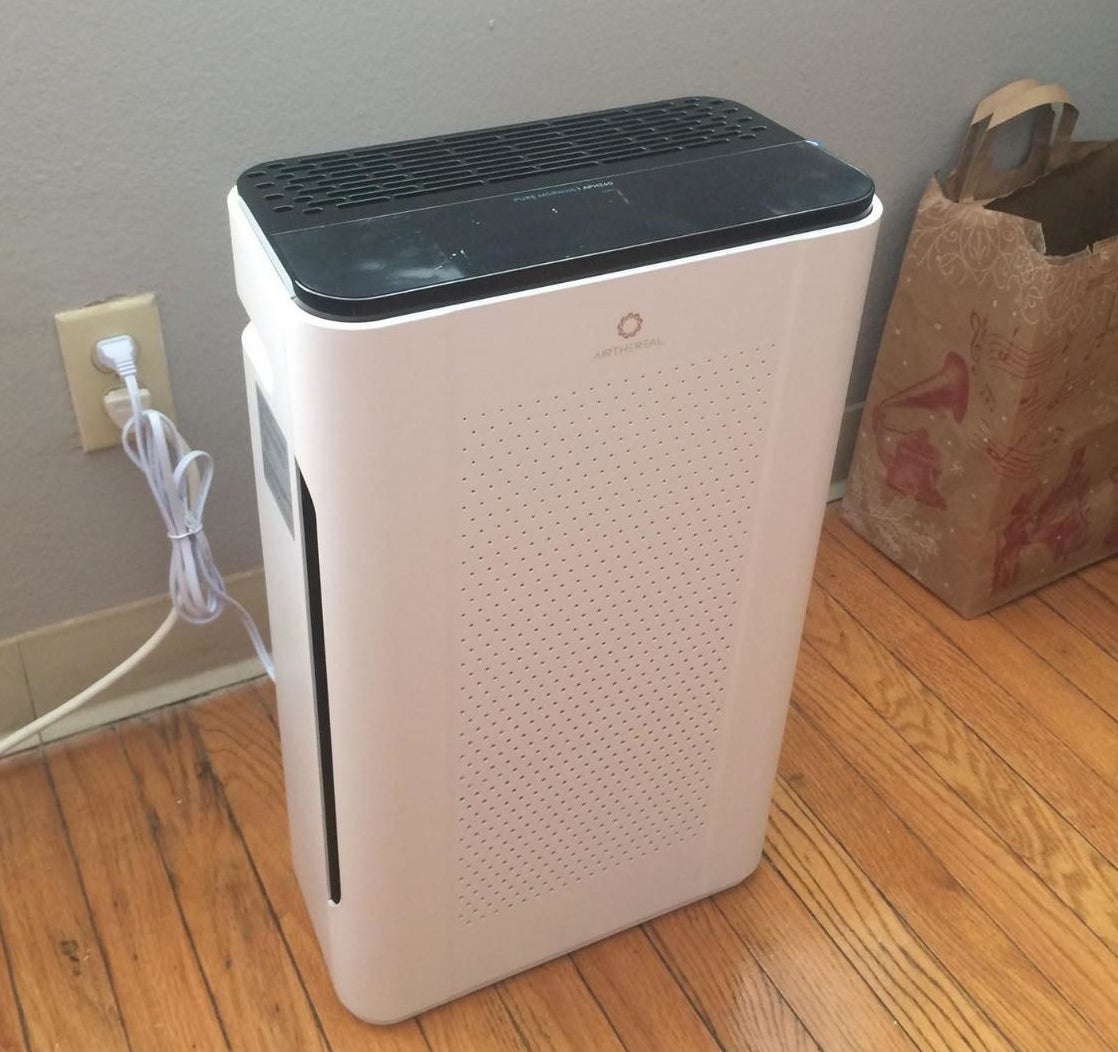 White air purifier with a black top on a floor