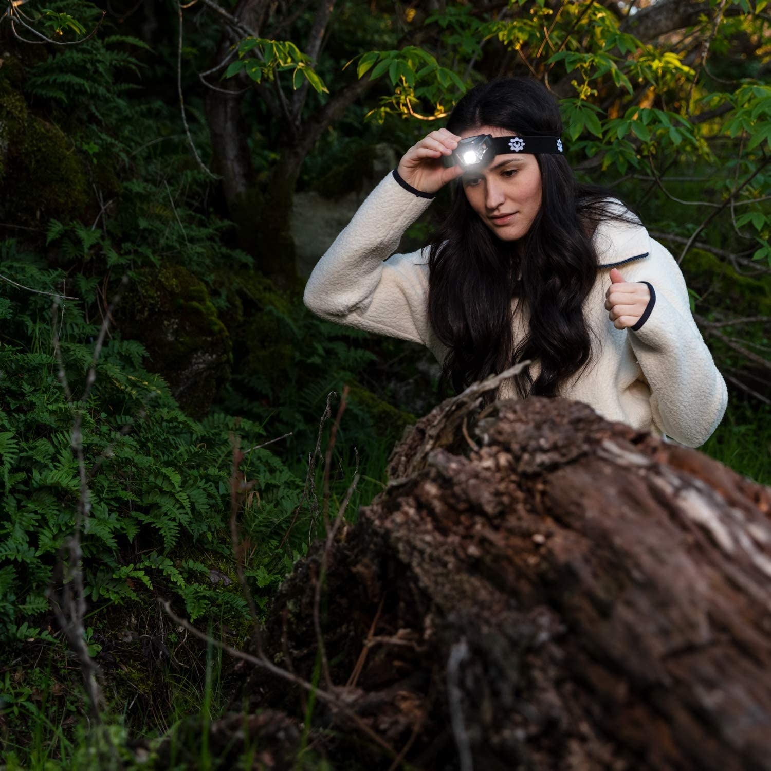 A model with the headlamp attached to their forehead while walking through woods 